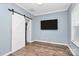 Bedroom with barn door, wood floors, and mounted TV at 19935 Wooden Tee Dr, Davidson, NC 28036