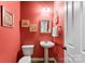 Stylish powder room with pedestal sink and coral walls at 7708 Spanish Oaks Dr, Waxhaw, NC 28173