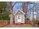 Charming backyard shed with a white door, surrounded by mature trees and a picket fence at 7708 Spanish Oaks Dr, Waxhaw, NC 28173