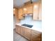 Well-lit kitchen with wood cabinetry, white backsplash, and black stovetop on white counter at 7932 Cedarsmith Ct, Charlotte, NC 28217