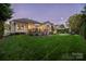 Backyard with illuminated home at dusk at 1108 Butterburr Dr, Matthews, NC 28104