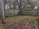 Partially fenced backyard with leaf covered ground at 1206 N Boyce St, Gastonia, NC 28052