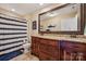 Well-lit bathroom with a granite countertop, wooden cabinets, and a shower with a striped curtain at 4006 Sincerity Rd, Monroe, NC 28110