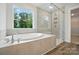 Bright bathroom with a soaking tub, a large window with nature views, and a tiled shower at 5404 Verona Rd # 36, Charlotte, NC 28213