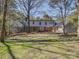 Green backyard view of a house with many windows, a screened in porch, and surrounding trees at 5529 Five Knolls Dr, Charlotte, NC 28226