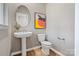 A stylish powder room featuring a pedestal sink, round mirror, and a modern, framed picture at 8022 Franklin Trail St, Mint Hill, NC 28227