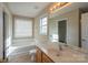 Bathroom with soaking tub, vanity, and tiled floor at 13406 Tartarian Ct, Charlotte, NC 28215