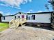 Tan mobile home with new wooden stairs and landscaping at 9763 Knightbridge Dr, Concord, NC 28025