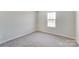 Empty bedroom with neutral carpet and paint, bright window, and electrical outlet at 1447 Honey Trl, Monroe, NC 28112