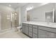 Bright bathroom featuring double sink vanity with gray cabinets, white countertop, and a glass enclosed shower at 1750 Blanche St, Charlotte, NC 28262