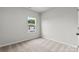 Well-lit bedroom with neutral walls and carpet, featuring a window with green tree views at 1750 Blanche St, Charlotte, NC 28262