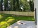 A view of the backyard fence with the grass lawn extending the length of the property and a concrete patio section at 211 Chestnut St, Shelby, NC 28150