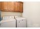 Bright laundry room, featuring washer, dryer, and ample wood cabinets at 355 Sardis Rd N Alt Rd, Charlotte, NC 28270