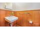 Small half bathroom with wood paneling and pedestal sink at 4201 Westridge Dr, Charlotte, NC 28208