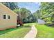 Spacious backyard with a brick house, wooden deck, storage shed, and concrete walkway surrounded by lush greenery at 1769 Old Nc 27 Hwy, Mount Holly, NC 28120