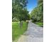 Gravel driveway lined with mature trees on a lush green lawn, creating a picturesque entrance to the property at 1769 Old Nc 27 Hwy, Mount Holly, NC 28120