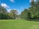 Sprawling green lawn with mature trees, and a charming home nestled in the background, evoking a peaceful retreat at 1769 Old Nc 27 Hwy, Mount Holly, NC 28120