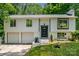 Charming split-level home featuring a two-car garage and updated black trim windows, nestled in a lush, green setting at 6726 Wannamaker Ln, Charlotte, NC 28226