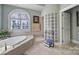 Bathroom featuring a soaking tub, glass block shower, and plenty of natural light from an arched window at 115 Amelia Ln, Mooresville, NC 28117