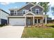 Charming two-story home featuring gray siding, brick accents, and a welcoming light blue front door at 115 Obadiah Ct, Troutman, NC 28115