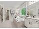 Bright bathroom featuring a large soaking tub, double vanity, large window, walk-in shower, and wood look tile floors at 13312 Chopin Ridge Rd, Huntersville, NC 28078