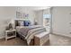 Bedroom featuring bed with wood trim, bench, and a window with a view of the neighborhood at 13312 Chopin Ridge Rd, Huntersville, NC 28078