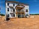 Two story new home construction showcasing unfinished backyard, deck structure, and house wrap under blue skies at 13312 Chopin Ridge Rd, Huntersville, NC 28078