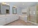 Bright bathroom featuring a soaking tub, double vanity, tiled floors, and a glass-enclosed shower at 6654 Kingbird Ct, Charlotte, NC 28215