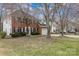 A beautiful two-story brick home with black shutters, surrounded by mature trees and a green lawn at 6654 Kingbird Ct, Charlotte, NC 28215