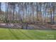 Well-maintained lawn with border of mature trees and landscape featuring retaining wall and fencing at 17627 Caddy Ct, Charlotte, NC 28278