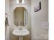 Well-lit half bath with pedestal sink, decorative mirror, and neutral wall color at 17627 Caddy Ct, Charlotte, NC 28278