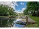 Beautiful waterfront property featuring a private dock, lush greenery, and calm water reflecting the sky at 1934 Hickory Hills Dr, Denver, NC 28037