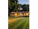 Inviting single-story home with a manicured lawn and warm exterior lighting at dusk at 206 Fox Den Rd, Troy, NC 27371