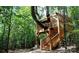 Whimsical wooden treehouse nestled among tall trees, featuring sturdy support beams and a staircase at 4774 Looking Glass Trl, Denver, NC 28037