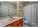 Traditional bathroom with wood vanity, light countertop, framed mirror, and shower/tub combination with white shower curtain at 5981 Bison Ct, Fort Mill, SC 29707