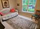 Cozy bedroom featuring a wicker daybed, floral area rug, and bright natural light from the large window at 5981 Bison Ct, Fort Mill, SC 29707