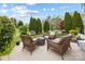 Backyard patio features wicker furniture, mature landscaping and stone hardscaping at 5981 Bison Ct, Fort Mill, SC 29707