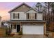 Two-story home showcasing stone accents and a two-car garage against a serene sunset backdrop at 6204 Springbeauty Dr, Charlotte, NC 28227