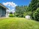Expansive backyard with a well-maintained lawn, mature trees, and a charming white storage shed at 9903 Southampton Commons Dr, Charlotte, NC 28277