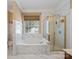 Spa-like bathroom featuring a soaking tub, separate shower, and marble tile throughout at 9903 Southampton Commons Dr, Charlotte, NC 28277