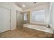 Spa-like bathroom featuring a soaking tub, glass-enclosed shower and travertine tile at 1102 High Brook Dr, Waxhaw, NC 28173