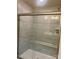 Shower with glass enclosure, built-in seat, and gray tile surround at 605 Nesbe St # 2228, Lancaster, SC 29720