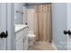 White vanity, beige shower curtain, and toilet in a small bathroom at 123 Kingfisher Dr, Mooresville, NC 28117