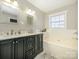 Bathroom with double vanity, bathtub, and dark cabinets at 9182 Bonnie Briar Cir, Charlotte, NC 28277