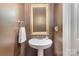 Powder room with pedestal sink, decorative mirror, and dark brown walls at 14839 Rocky Top Dr, Huntersville, NC 28078