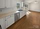 Bright kitchen featuring white cabinets, stainless steel appliances, and wood flooring leading to a dining area at 2823 Edsel Pl, Charlotte, NC 28205