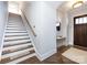 A staircase with carpeted steps, wooden handrail, and a stylish entryway table with a round mirror at 1012 Rockway Dr, Charlotte, NC 28205