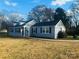 Charming single-story home featuring a light blue exterior with dark shutters and mature trees around the property at 2801 Cowles Rd, Charlotte, NC 28208