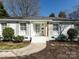Inviting front exterior featuring white brick, grey shutters, manicured bushes and a charming front door at 7037 Wrentree Dr, Charlotte, NC 28210