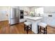 Modern white kitchen features stainless steel appliances, a center island with seating, and hardwood floors at 7037 Wrentree Dr, Charlotte, NC 28210
